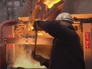 Foundry worker monitoring molten metal at a high temperature melting furnace